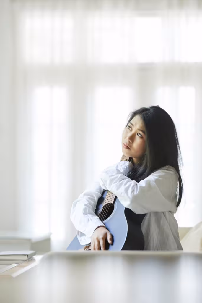 Woman with guitar sitting at home